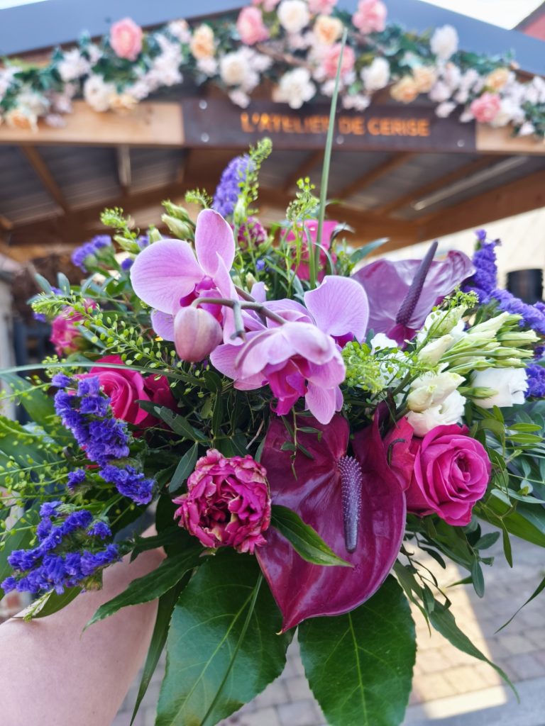 Bouquet de fleurs coupées, composé d'orchidée, de zantedeschia, roses, pivoine, statice, lisianthus et feuillages.